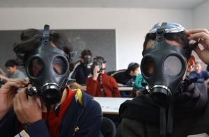 students wear gas masks during a war exercise in a school