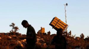 Israeli soldiers walk next to an Iron Dome missile interceptor battery as it is being positioned on the outskirts of Jerusalem