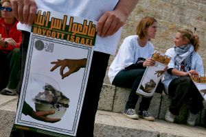 Internatinal peace activists holds posters calling to boycott Israel during a protest outside the Damascus Gate in Jerusalem