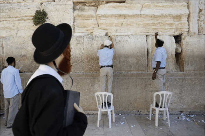 Zum bevorstehenden Passachfest entfernen diese beiden Männer Zettel aus der Klagemauer.